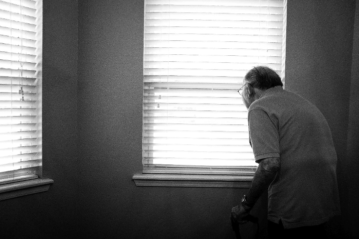 Photo of an elderly man looking out the window