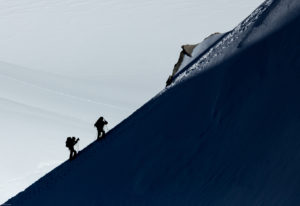 figures climbing a steep mountain slope