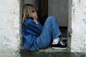 Lonely girl sitting in a doorway