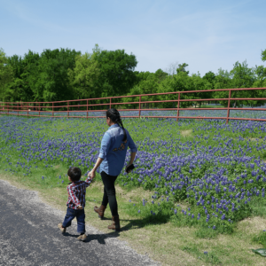 rural communities - mother and child walking by a field of bluebonnets