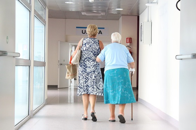 Woman and elderly mother walking down a hospital hallway