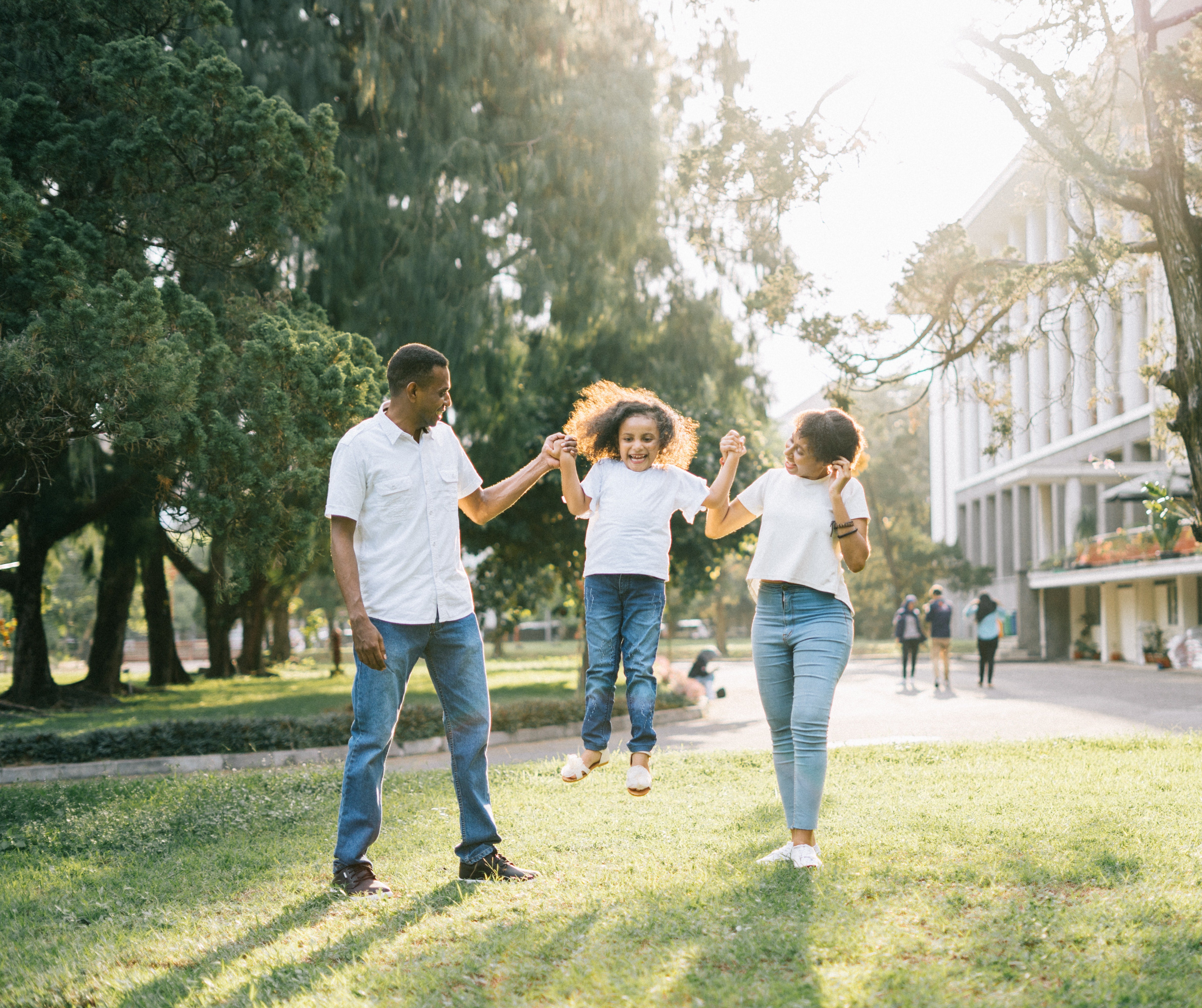 A stock photo of parents playing swinging daughter in the air