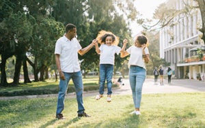 A stock photo of parents playing swinging daughter in the air