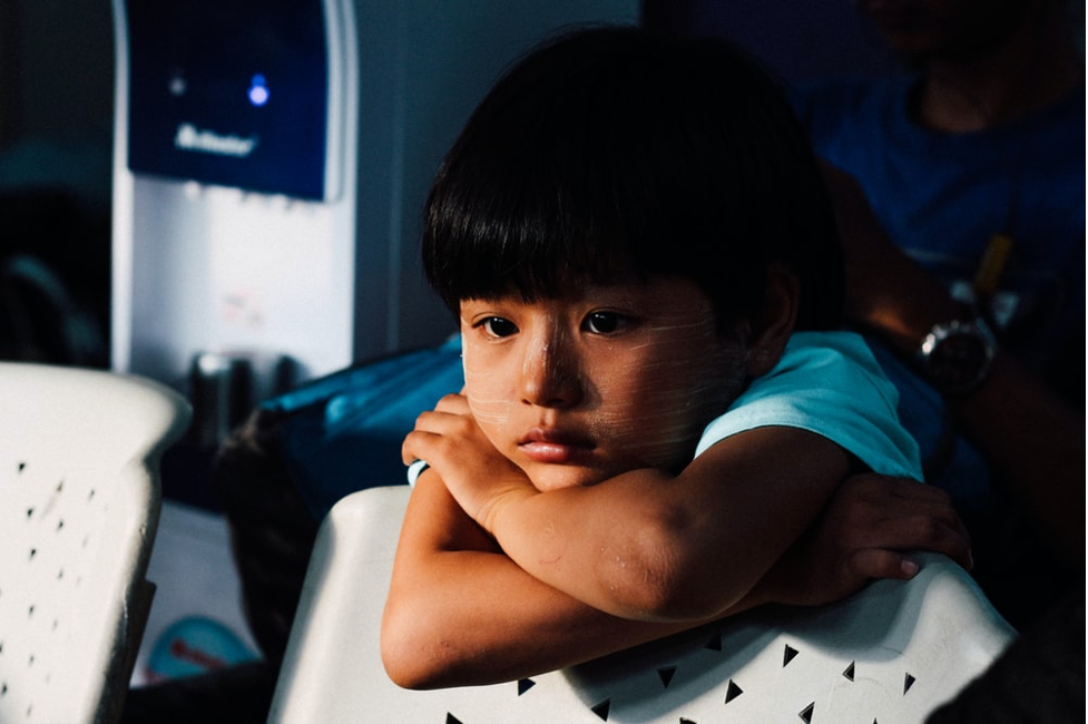 A photo of a sad child leaning on a chair