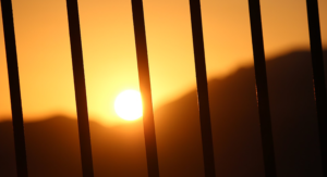 vaccine equity for the incarcerated - image of rising sun seen through prison bars