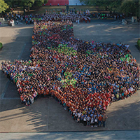 Large group of people in colorful shirts forming the shape of Texas.