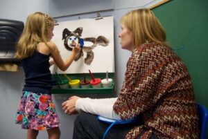 Woman with child painting on easel