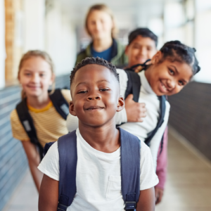 Group of school kids peaking from behind young boy