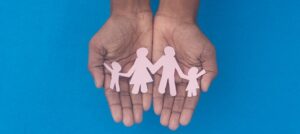 Hands holding paper cutout of family