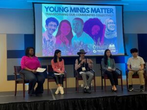 Opening panel discussion at Young Minds Matter 2023: five panelists on stage, seated in front of the Young Minds Matter banner