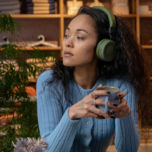 Woman with coffee and listening to headphones.