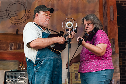 community-web man and woman playing instruments on a stage